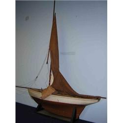 An early 20th century pond yacht, boarded decks above the white hull and lead weighted keel, the ma.