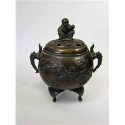 A 19th century Chinese bronze censer, the pierced cover surmounted by a squatting boy, the oval sec.
