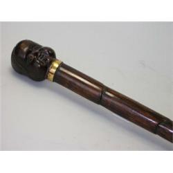 A late 19th century walking cane, the Japanese pommel carved as Okame on one side and a man's head..