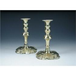 A pair of early George III brass petal base candlesticks, the shaped square feet and column knops w.