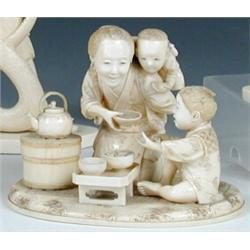 An early 20th century Japanese ivory group of a mother with one child on her back as she passes a b.