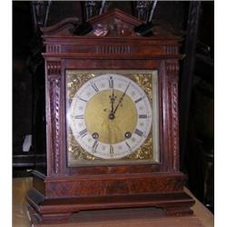 A late Victorian walnut mantle clock, the rectangular case with broken pediment above square brass..