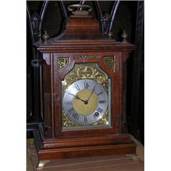 A Georgian style walnut mantle clock, the case with inverted bell top and handle above the arched b.