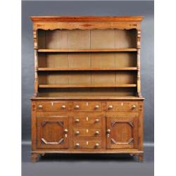 An 18th century oak Welsh dresser, the closed upper section with moulded cornice above an inlaid sh.