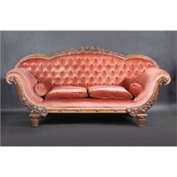 A Victorian oak framed scroll end settee, the foliate carved arched top rail above a padded button b