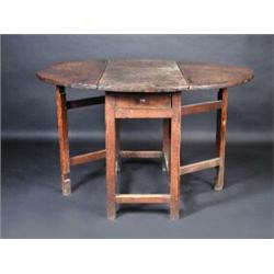 An 18th century oak drop leaf table, the circular twin flap top above an end frieze drawer, standin.