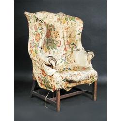 An early George III mahogany wing armchair, with worn upholstery, on square legs with H-shape stret.