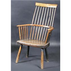 A 19th century ash and elm primitive comb back Windsor chair, the bowed top rail above a spindle ba.