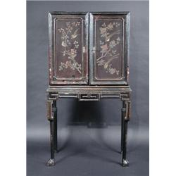 A Chinoiserie decorated lacquered cabinet on stand, the upper section with a pair of panelled doors.