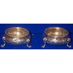 A PAIR OF EMBOSSED CIRCULAR SALT CELLARS, LONDON 1881, with beaded rims, each raised on three...