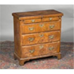 A WALNUT CROSSBANDED BACHELORS CHEST, 18th CENTURY, the moulded fold out top with indented cor...