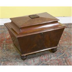 a mahogany wine cooler, early 19th century, sarcophagus shaped, the lid with ribbed finial, th...