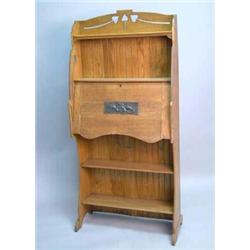 An Arts and Crafts oak students desk, with open shelves and fall front applied with a copper pane...