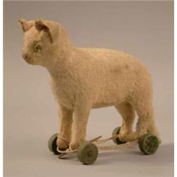 A Steiff white cat toy, with green glass eyes and wooden wheels. height 6.75in....