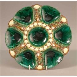 A Minton majolica oyster plate, decorated with shells against a marbled green ground. 9in....