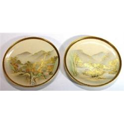 Two Japanese Satsuma plates hand painted and gilded with trees and village scenes beneath mountains,