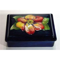 Rectangular Moorcroft box and cover, hand painted and tubelined with a clematis onto a dark blue gro