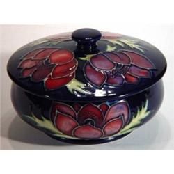 Moorcroft circular box and cover hand painted and tubelined with anemones onto a dark blue ground, i