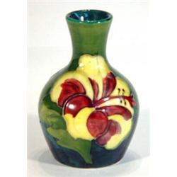 Small Moorcroft vase hand painted and tubelined with 'Hibiscus' pattern onto a green and blue ground