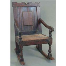 A 17th century oak panel back rocking chair, engraved 'Ruth 1689' on baluster legs...
