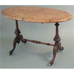 A Victorian inlaid figured walnut oval occasional table, on carved end standards, fitted china ca...