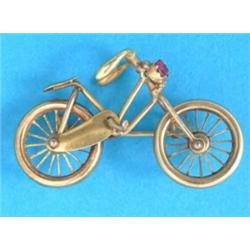 A 15ct gold brooch, in the form of a bicycle, the headlamp set with a red stone...