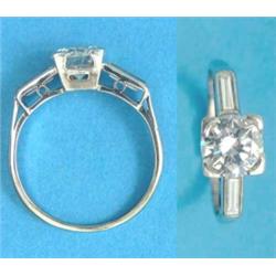 A white gold solitaire diamond ring, the claw set brilliant cut diamond flanked by baguette cut d...