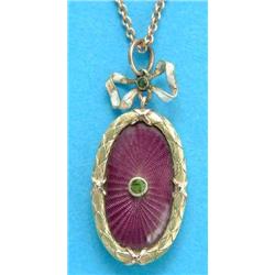 A small Edwardian 2-colour gold oval pendant, with purple guilloche enamelling in a laurel wreath...