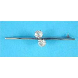 A 2-stone diamond crossover bar brooch, the old brilliant cut stones claw set in white metal, eac...