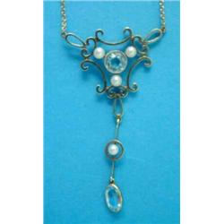 An Edwardian 15ct gold pendant necklace, of openwork scroll design, set with an aquamarine and se...