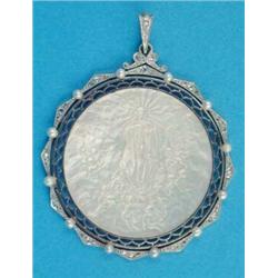 A gold and platinum mounted circular pendant, inset with a mother of pearl plaque carved with a s...