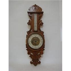 AN OAK WHEEL BAROMETER, late 19th century, elaborately carved case, thermometer over registar dia...