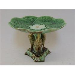 A MAJOLICA DESSERT COMPORT, c.1880, modelled as a lily pad, supported by three stork figures, tre...
