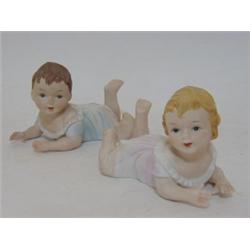 A PAIR OF TINTED BISQUE PIANO BABIES, 20th Century, length 15cm (2)  £80-100...