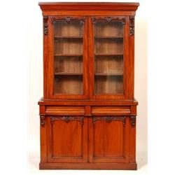 A Victorian Mahogany Bookcase, a pair of glazed doors flanked by carved corbels, above two short...