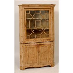 A Stripped Pine Corner Cupboard, the Greek key moulded cornice above a glazed door, enclosing two...