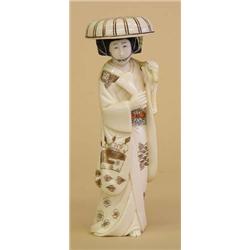 CARVED AND POLYCHROMED IVORY FIGURE OF A GEISHA, Japanese. Signed. The walking female wearing a...