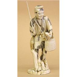 CARVED IVORY FIGURE OF A FISHERMAN, Japanese. 20th Century. Walking among tree trunks with a st...