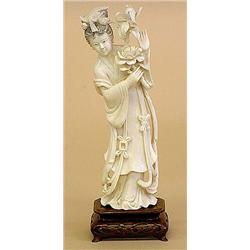 CARVED IVORY FIGURE OF GUANYIN, Chinese. The immortal wearing a long robe tied at the waist hol...