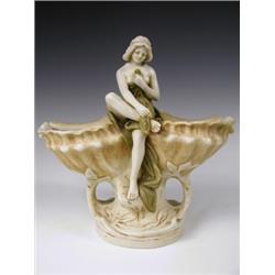 A Royal Dux figure modelled as a seated semi-clad female between two shells, pad mark to base,...