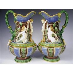 A pair of Minton Majolica ewers, decorated in relief with a cherub flanked by a merman and mer...