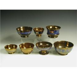 Seven copper lustre bowls, each with blue or mustard bands of decoration, two with moulded flo...