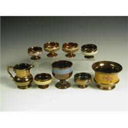 Six copper lustre salts, each raised on a low foot, a bowl, a goblet with a ribbed body and a...