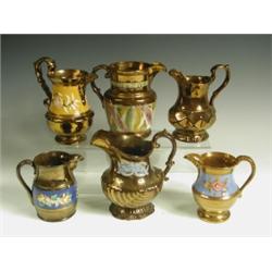 Six copper lustre jugs, each of shaped form, four with moulded floral sprays, one with stylise...