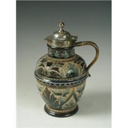 A Royal Doulton stoneware jug decorated with incised foliage below a plated cover, by Hukin &...