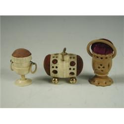 Three Victorian pin cushions: two in turned ivory , one with ring handles and one in turned ve...