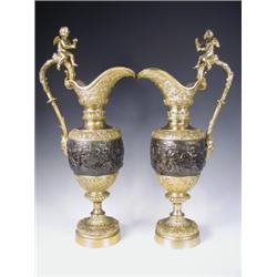 A pair of late l9th Century bronze and ormolu ewers, decorated with cherubs pursuing the arts...