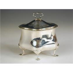 An Edwardian silver sucrier of oval lobed form, with a flush lid and ring handle on four paw f...