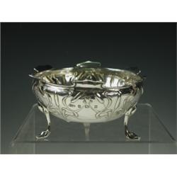 An Art Nouveau silver bowl embossed with bullrushes below a shaped rim, raised on 3 scrolled f...