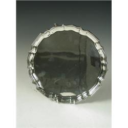 A silver card tray with a Chippendale shaped border raised on three scrolled feet, 1938, appro...